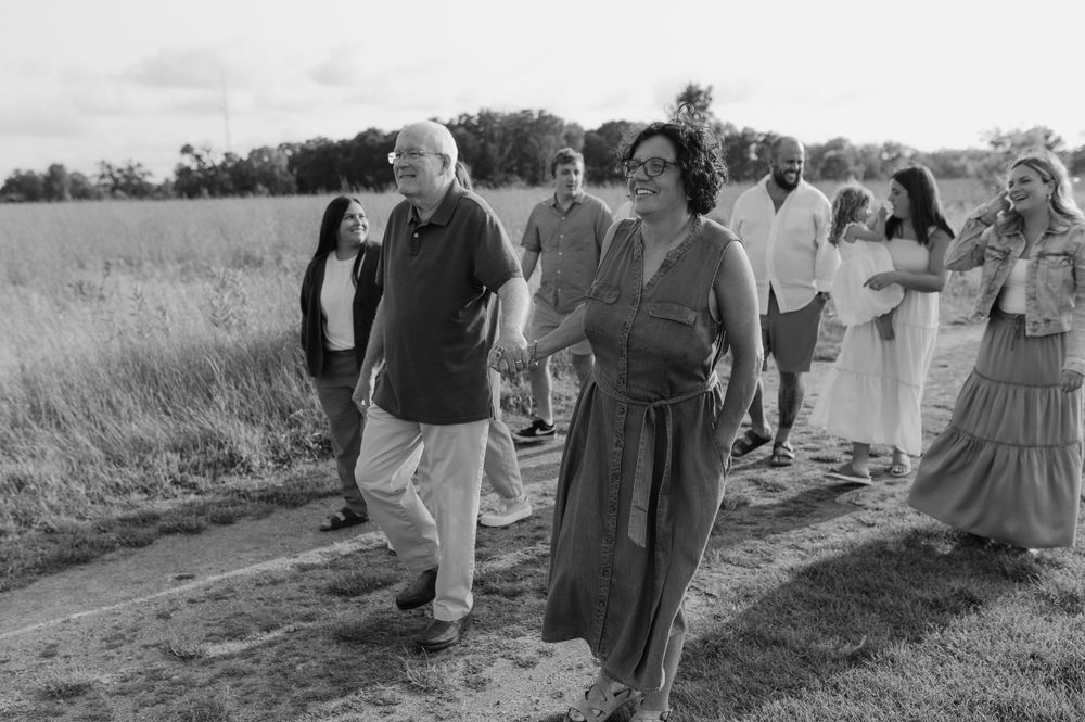 Group walking together on a dirt path through a scenic field at sunset.