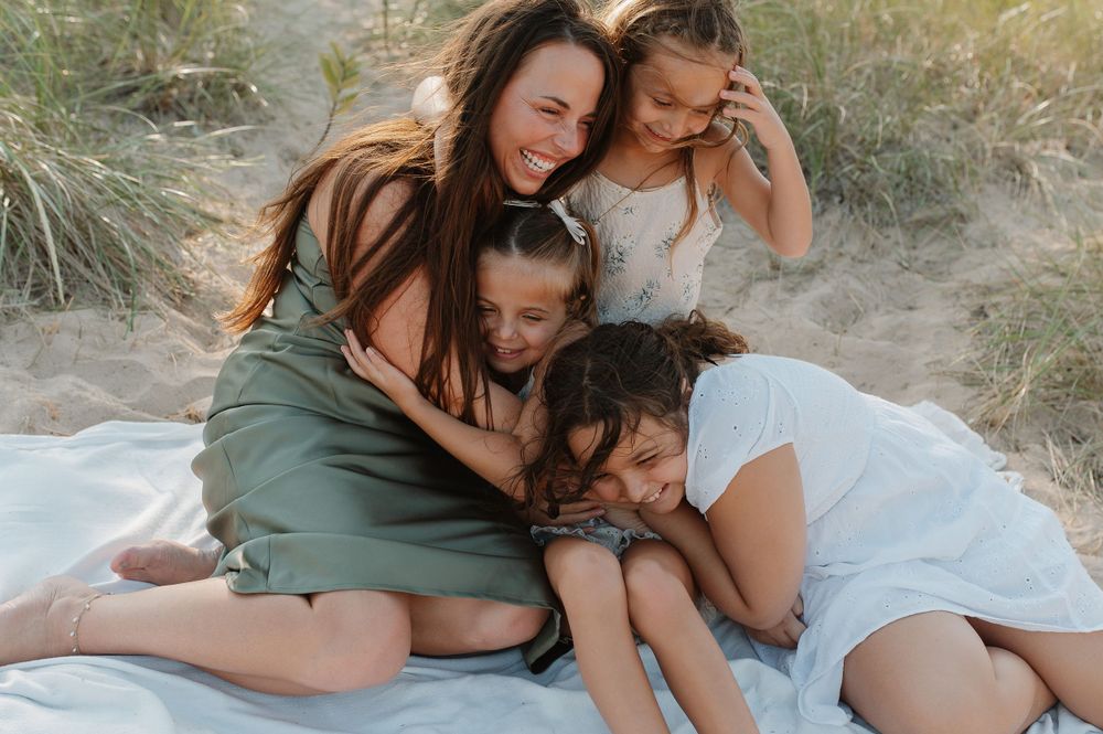Intimate family moment captured as they embrace on a blanket among coastal dunes.