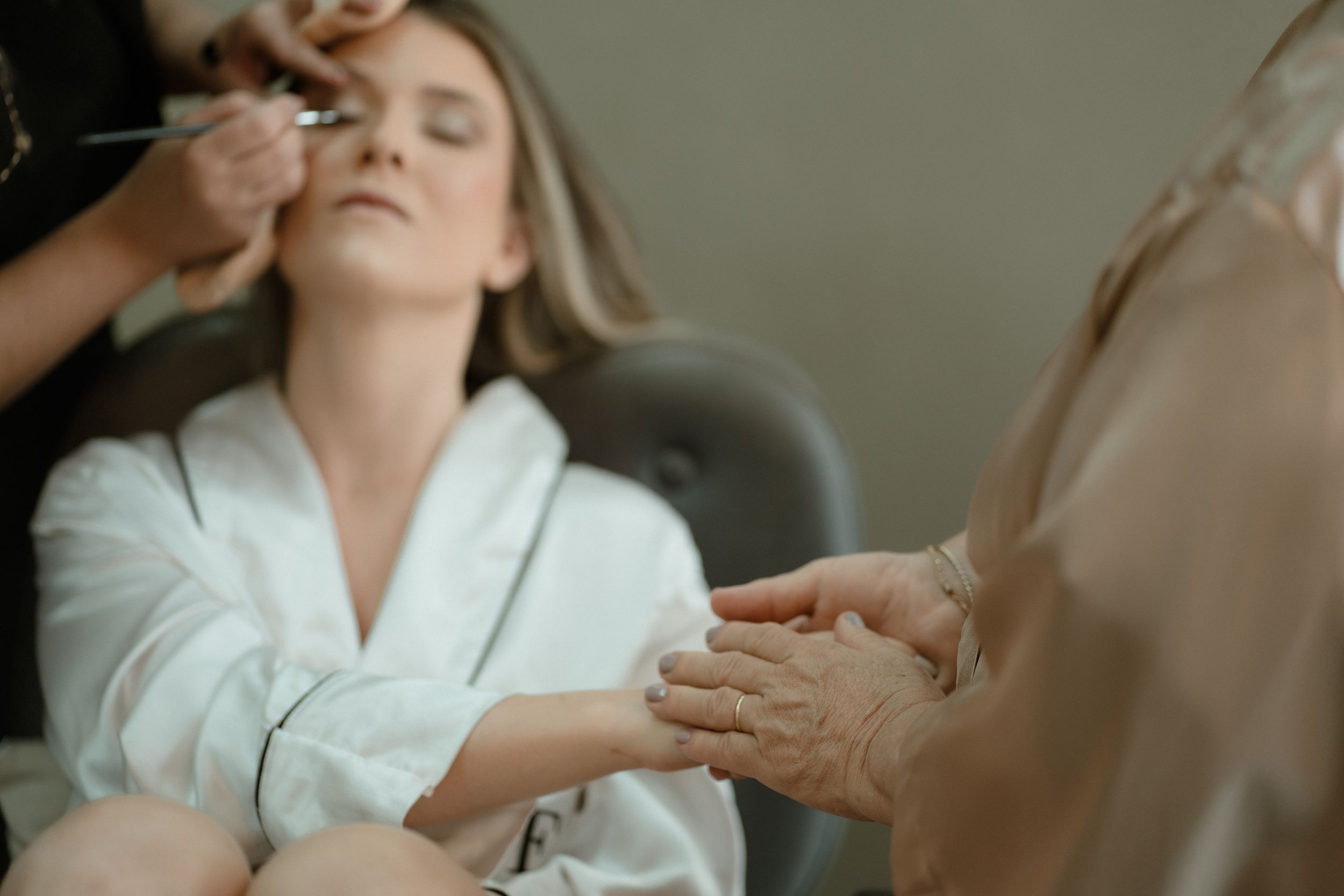 Soft-focus beauty preparation scene with makeup artist working in natural light.