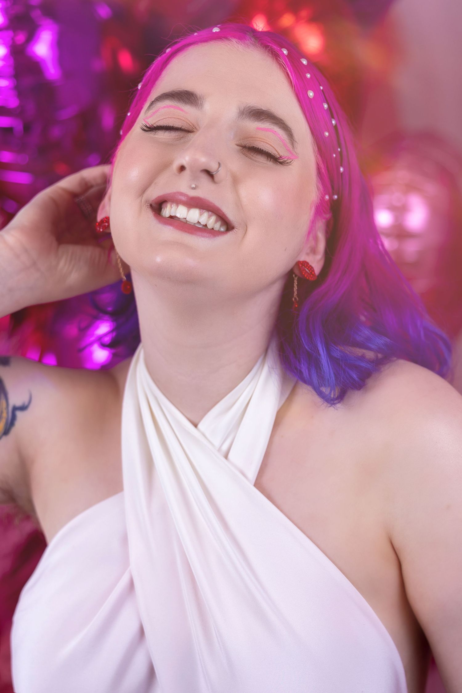 Non binary femme mode with colourful hair posing in a valentines themed shoot with balloons & disco balls wearing pink