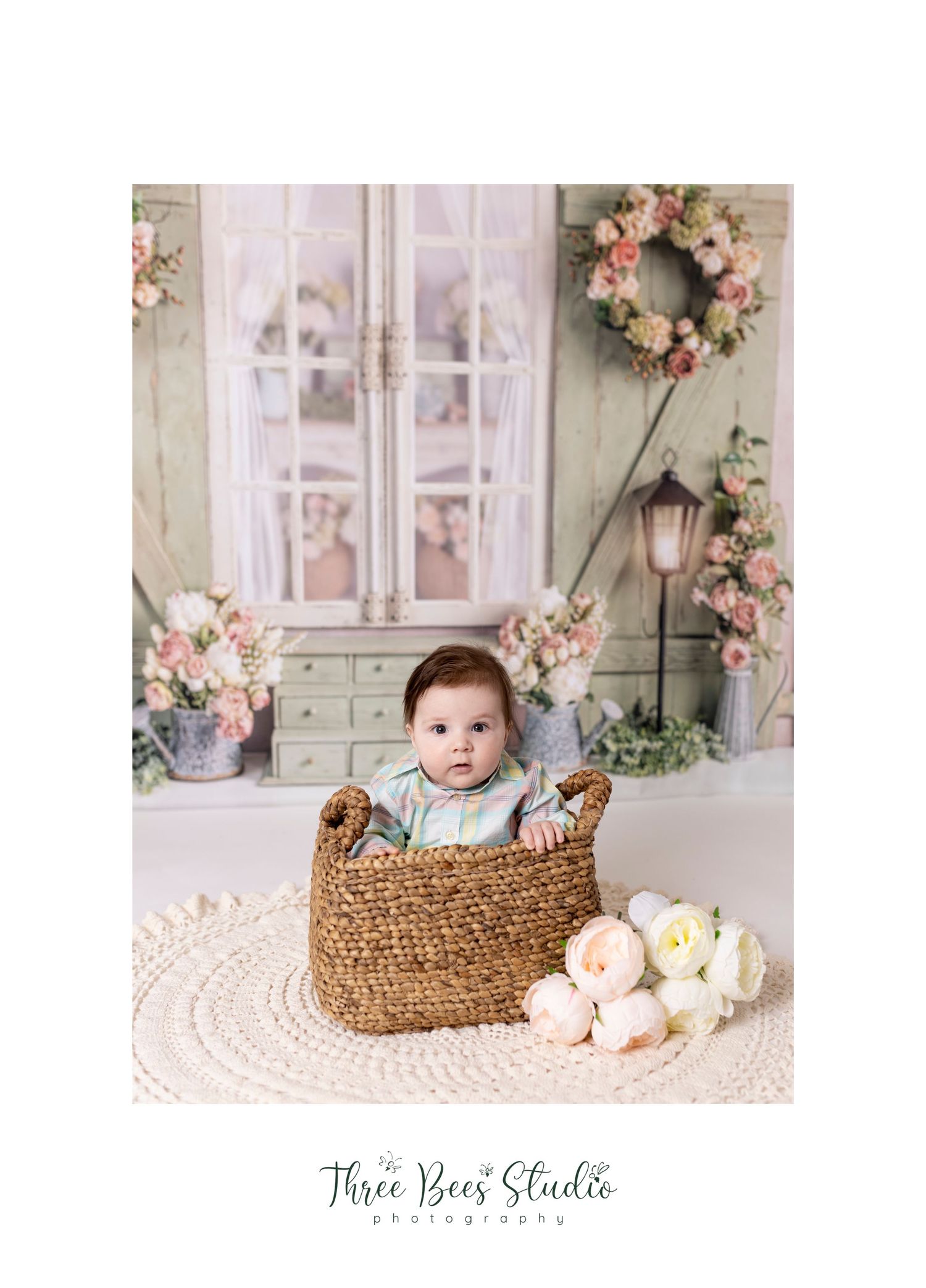 Rustic spring portrait with woven basket and white roses against vintage door backdrop.