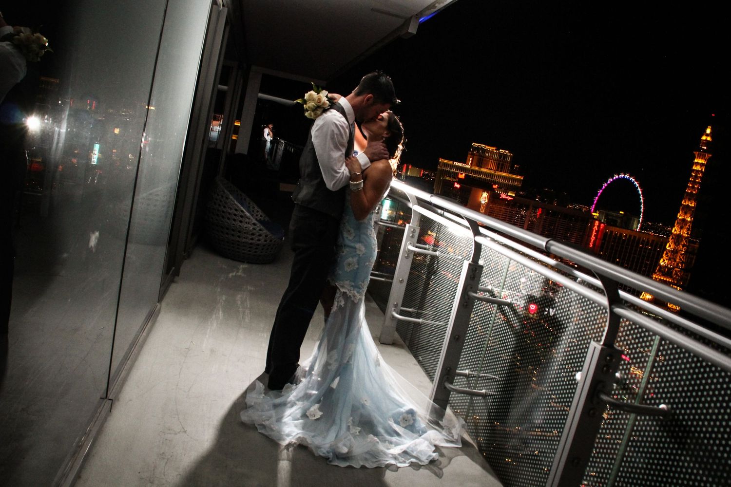 A dramatic nighttime wedding photo with the Las Vegas skyline visible in the background.
