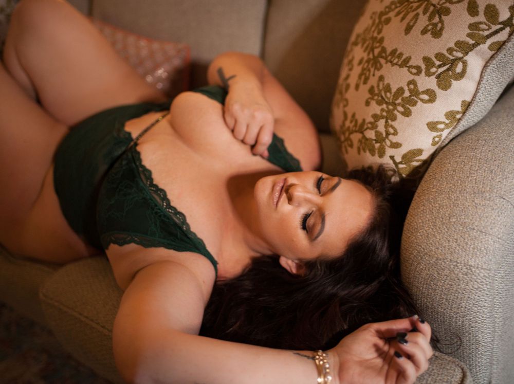 Intimate boudoir photo on grey couch with lace lingerie.