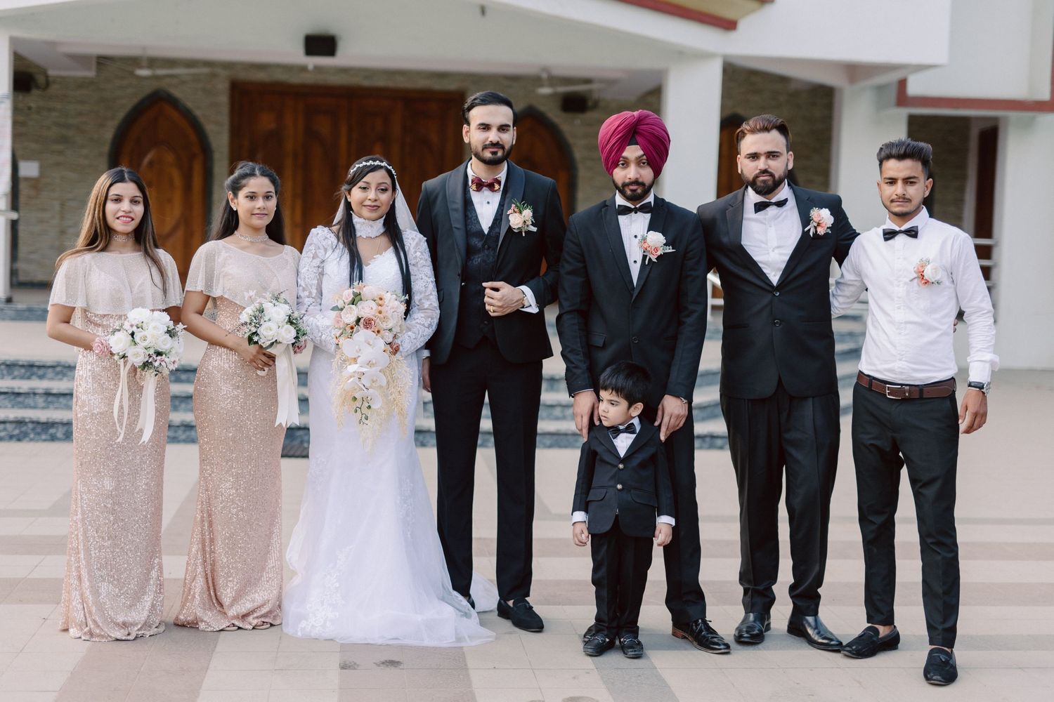 Wedding party in formal attire including bridesmaids in sequined gowns and groomsmen in tuxedos.