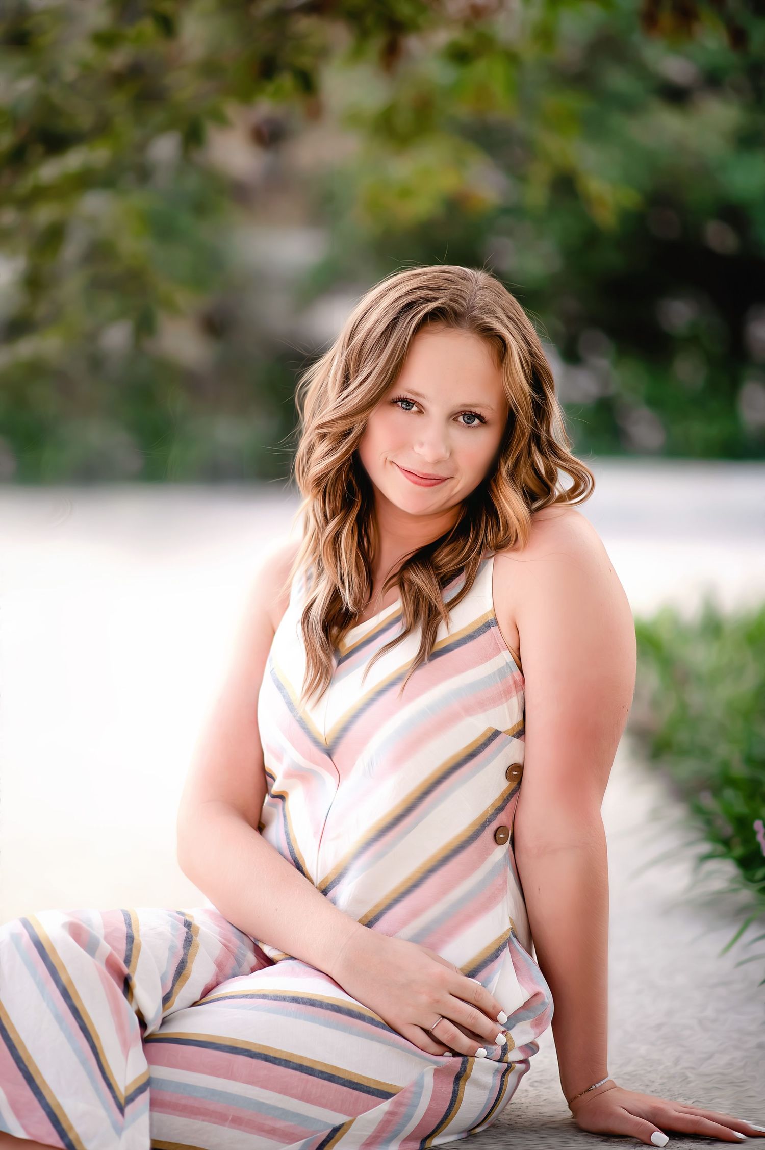 Woman in striped dress sits outdoors in natural lighting.