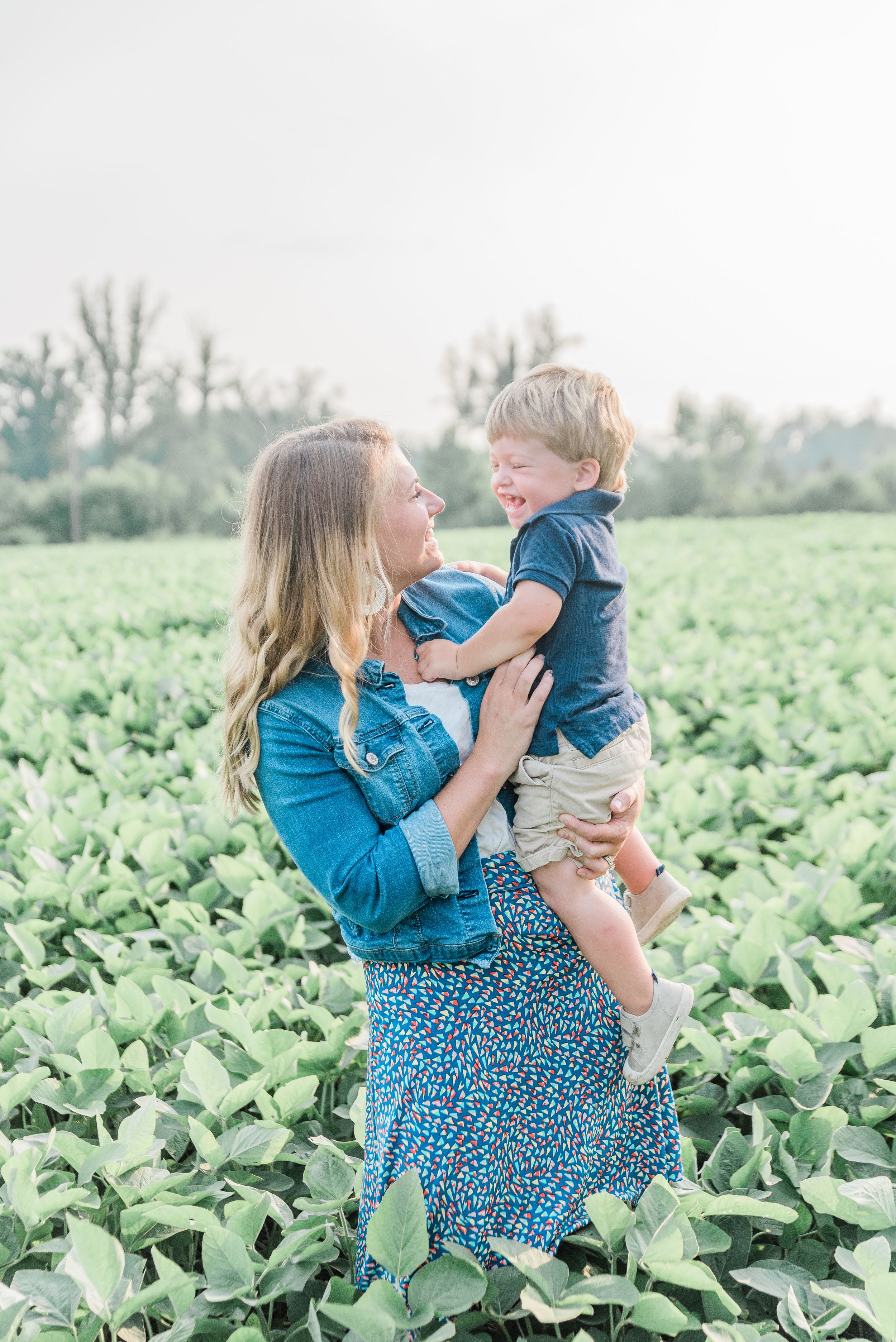 A touching moment between parent and child in a lush green soybean field on a bright summer day.