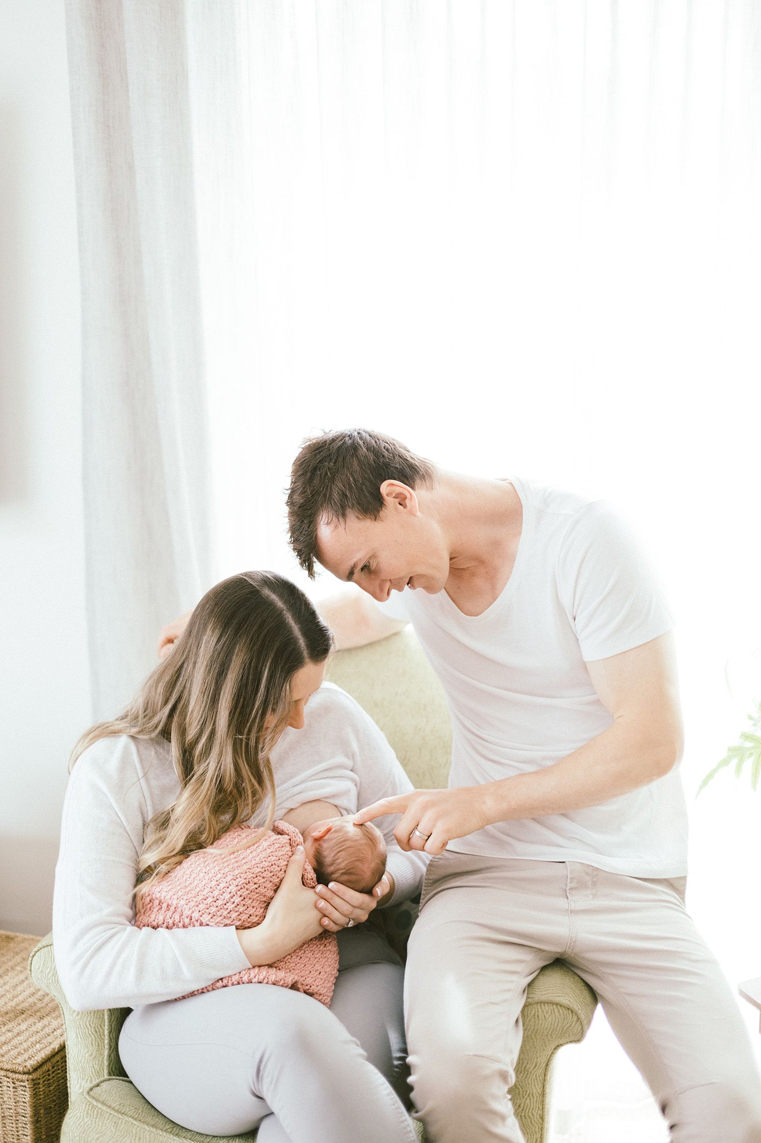 Tender family moment captured on a light-filled couch showing gentle interaction and bonding.