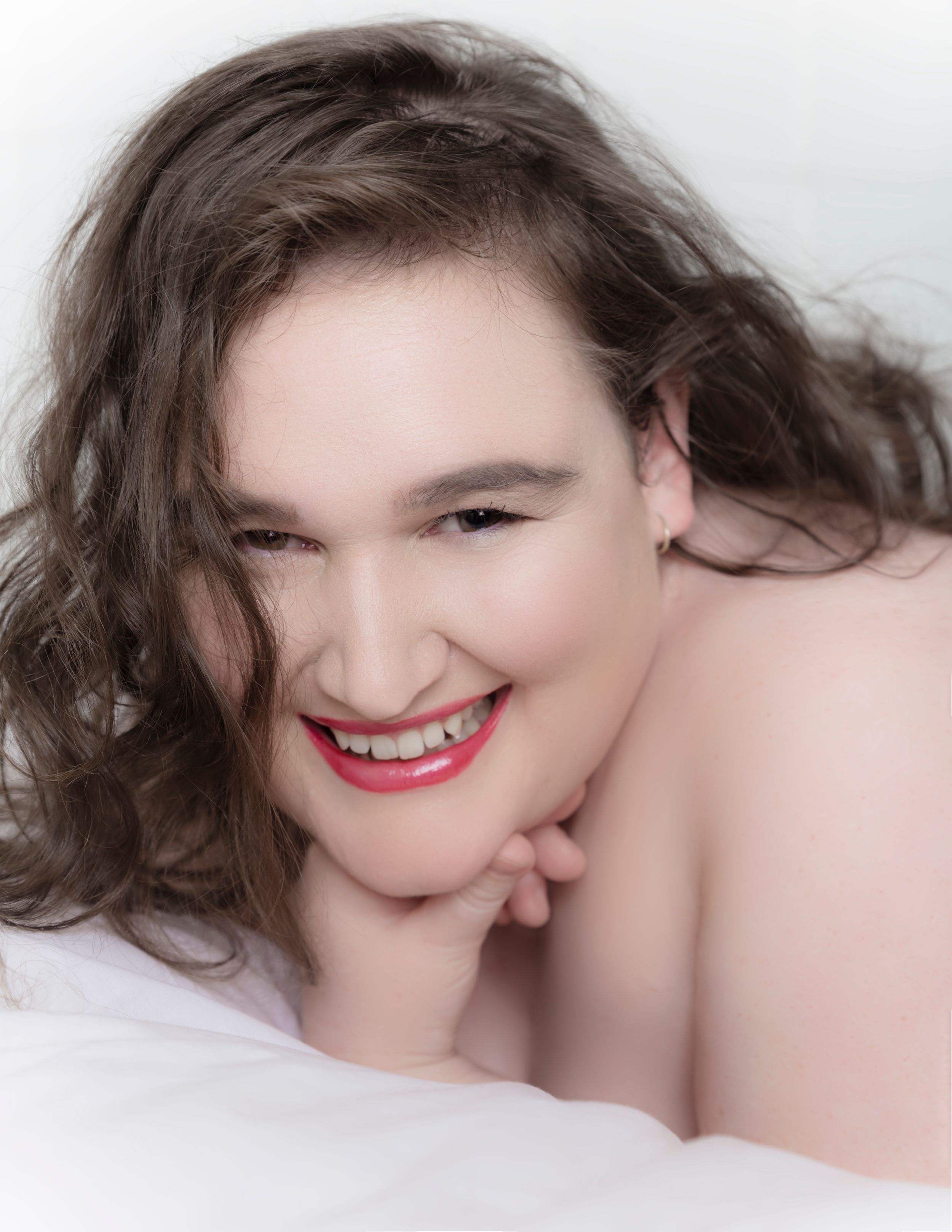 Close-up portrait with red lipstick and flowing dark hair against light background.