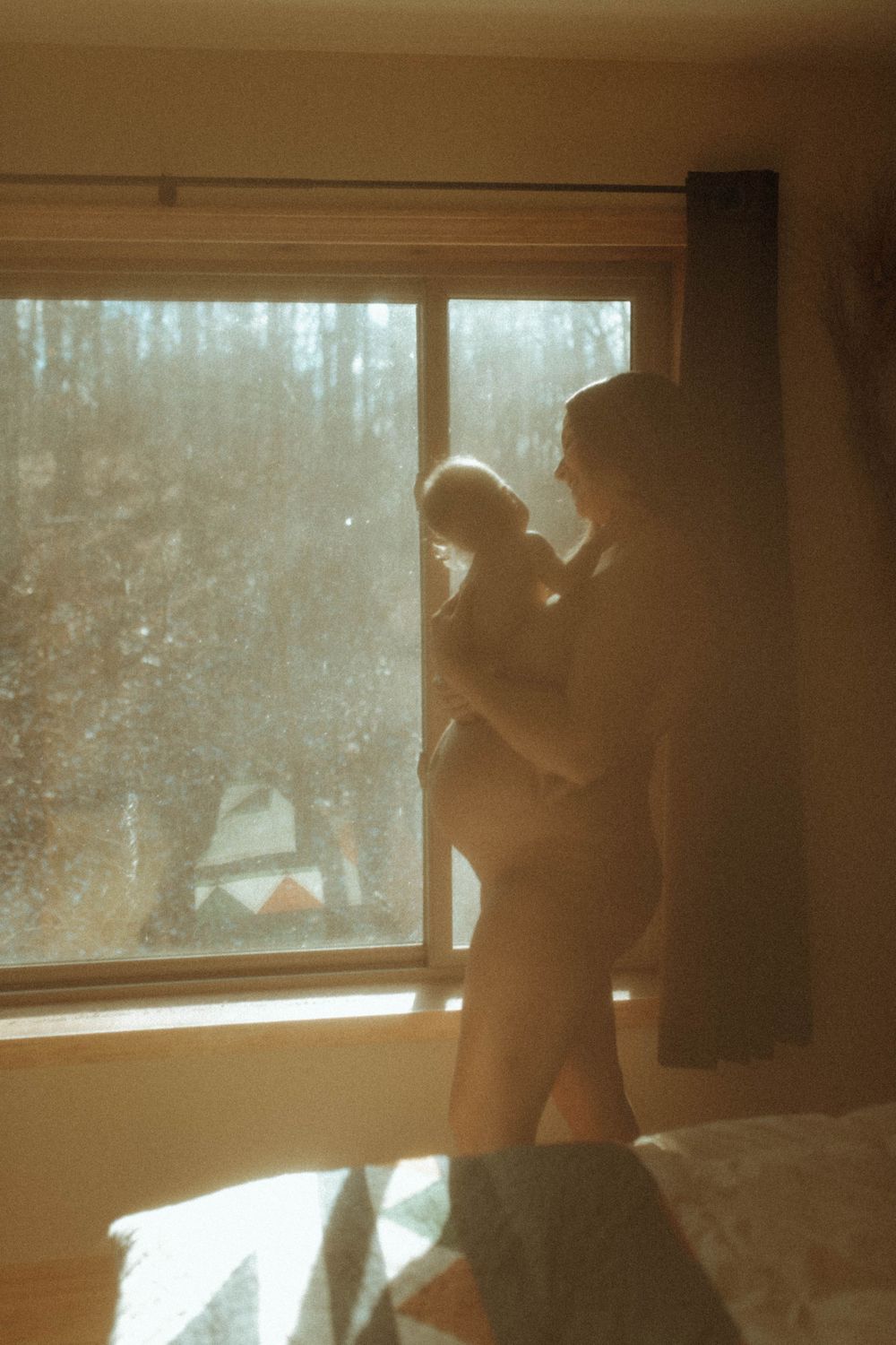 Silhouettes create a peaceful scene of bonding by a sunlit window.