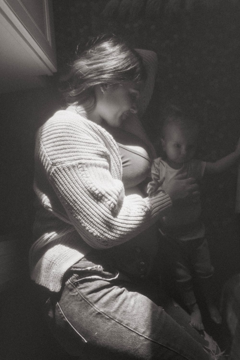 Black and white photograph capturing an intimate parenting moment indoors.