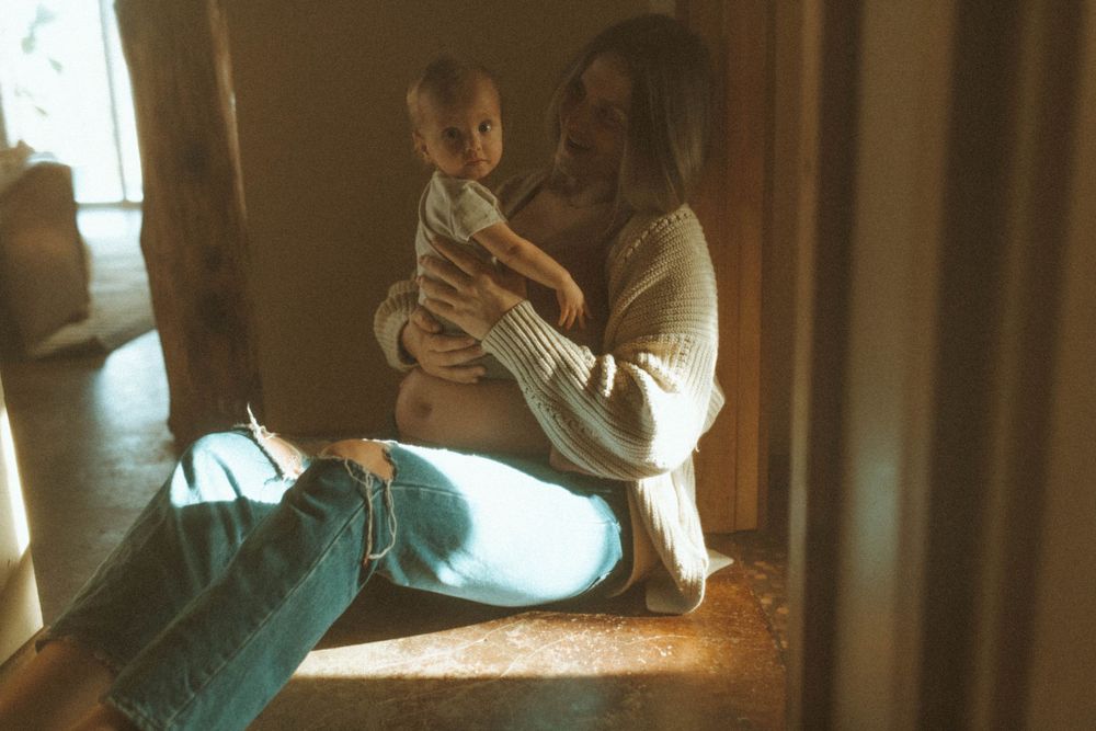 Intimate family moment captured by window light in vintage-style photography.