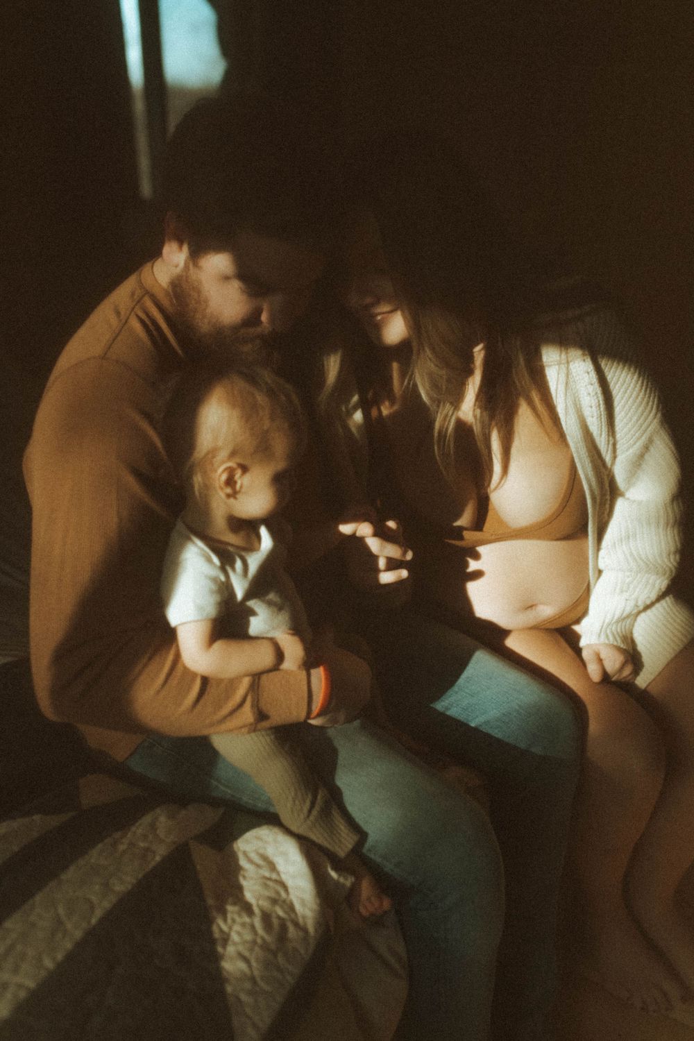 Tender family moment photographed in warm sepia lighting.