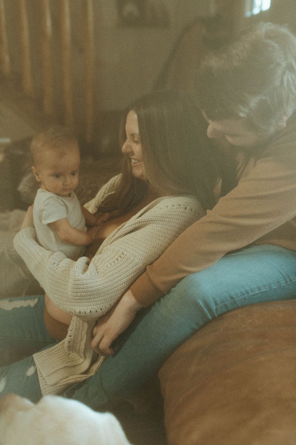 A tender family moment shared on a comfortable couch with warm sunlight streaming through the window.