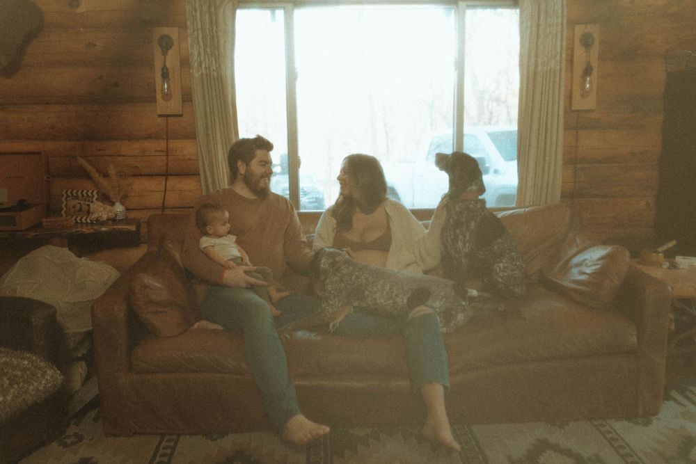 Family and pets lounging together on sofa in cozy log cabin interior.