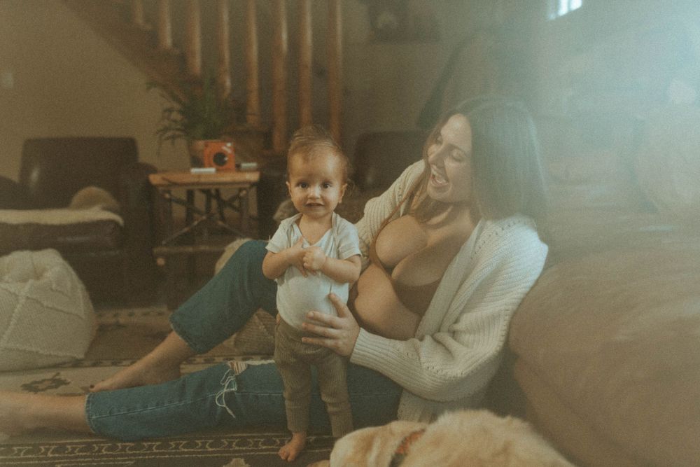 A candid moment in a sunlit living room with wooden stairs visible in the background.