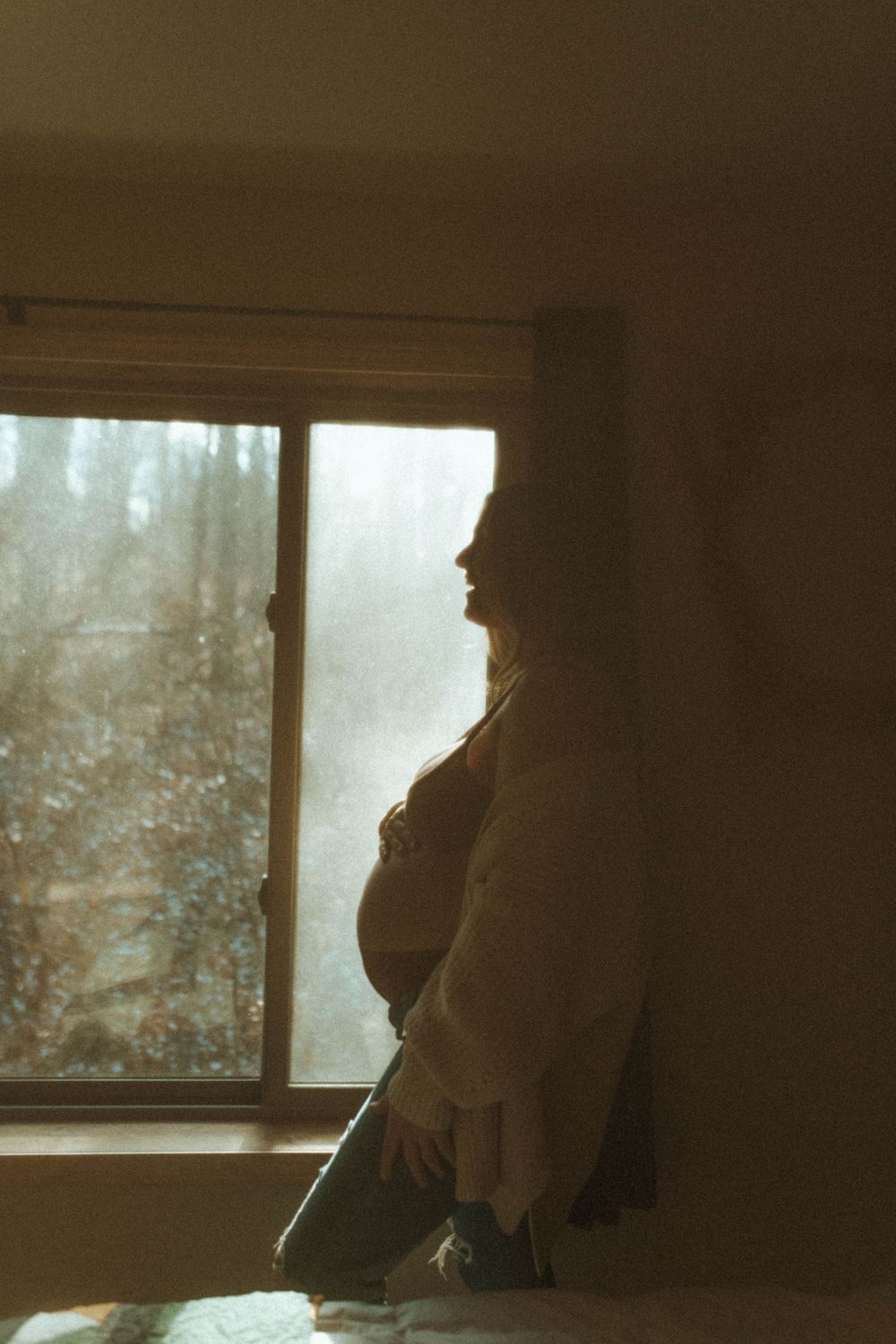 Silhouette figure standing by window in warm vintage lighting.