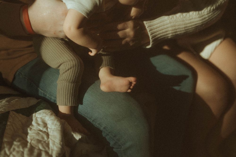 Close-up of hands and limbs in intimate family scene with sepia toning.