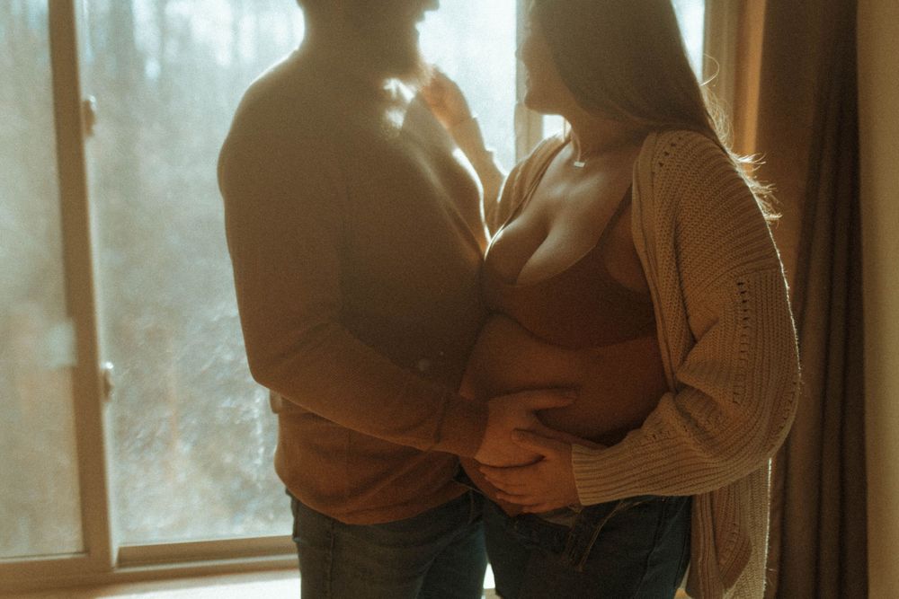A silhouetted couple shares an intimate moment by a window.