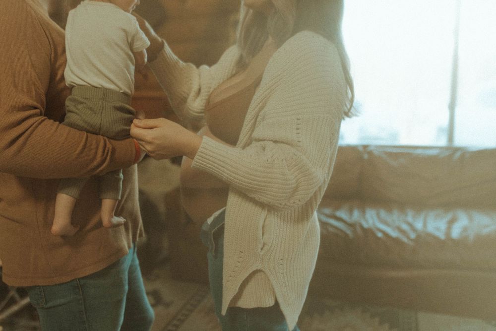 Two people share a tender moment together by a window in natural light.