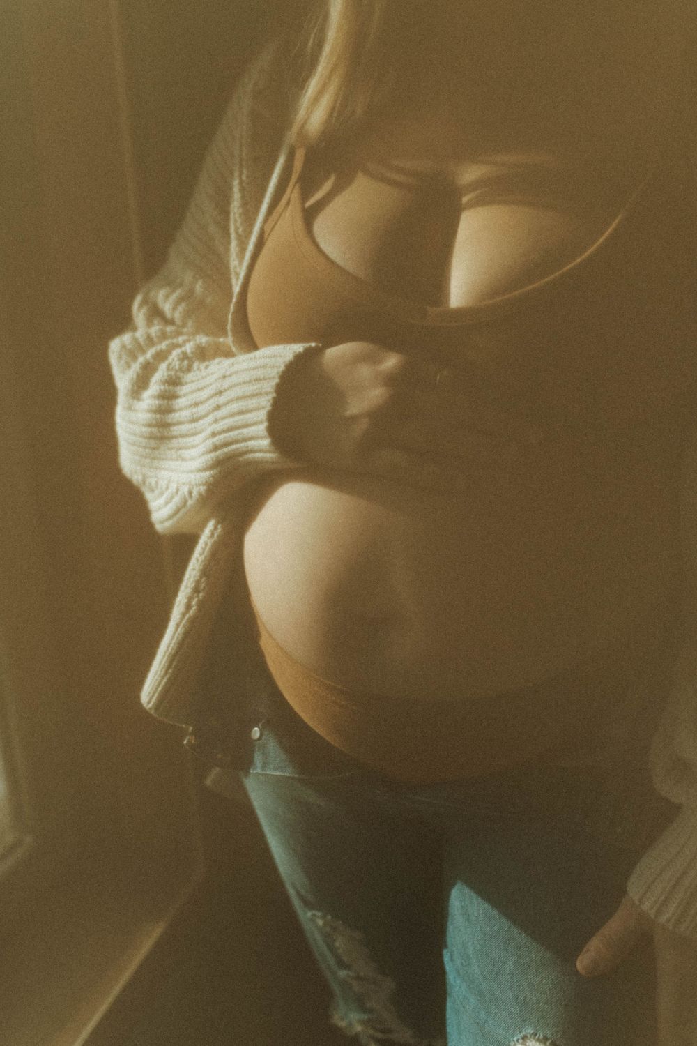 Close-up shot of torso in white knit sweater with sepia toning.