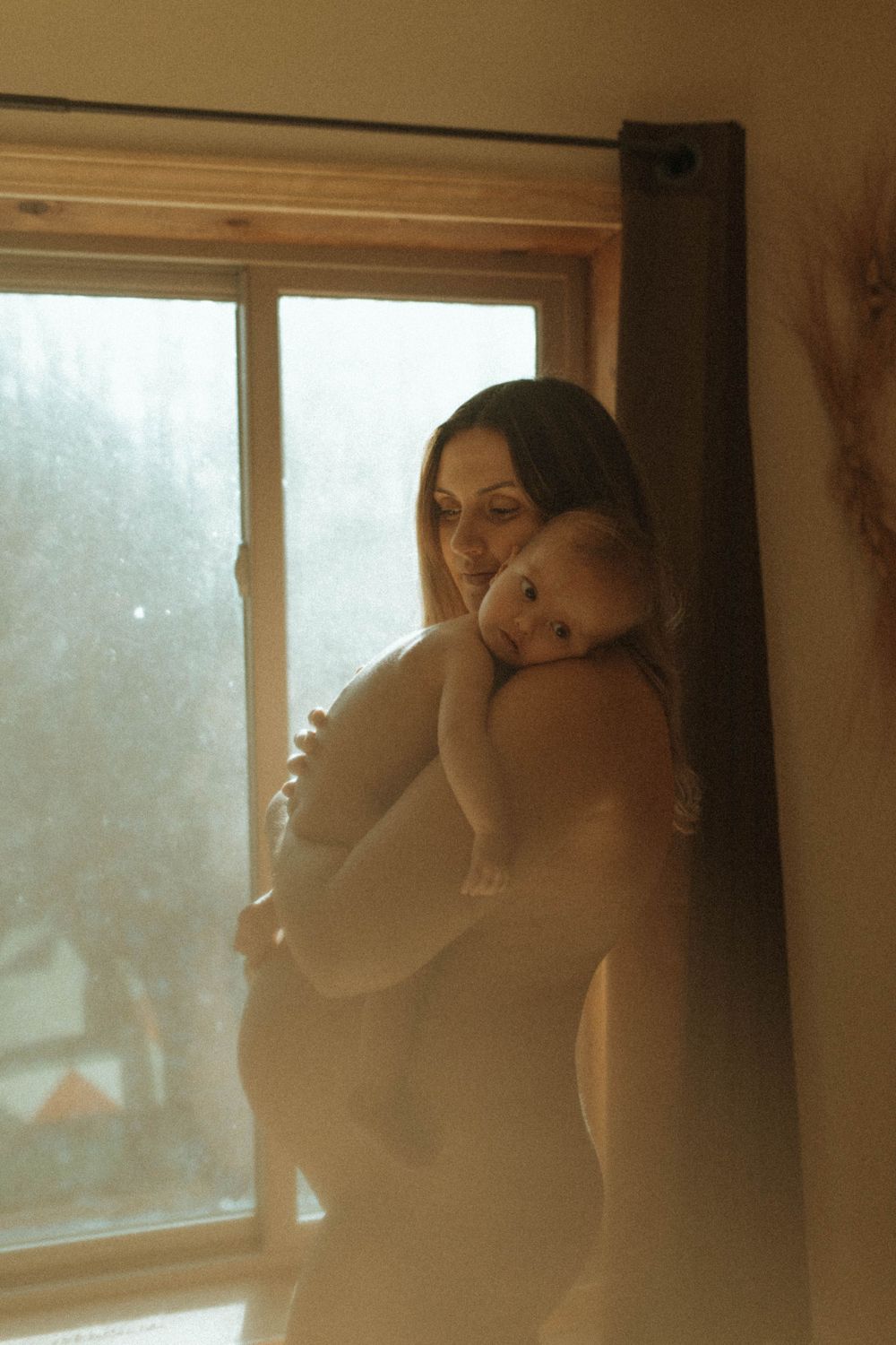A tender moment between parent and child silhouetted against a bright window.