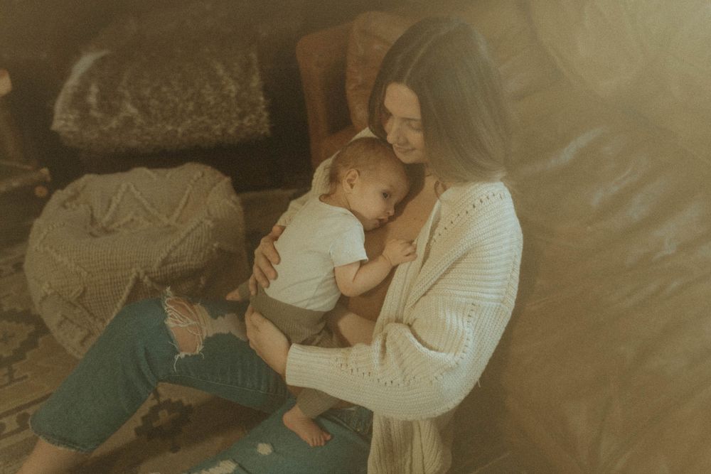 A warm-toned photograph capturing a tender moment between parent and child in a cozy living room.