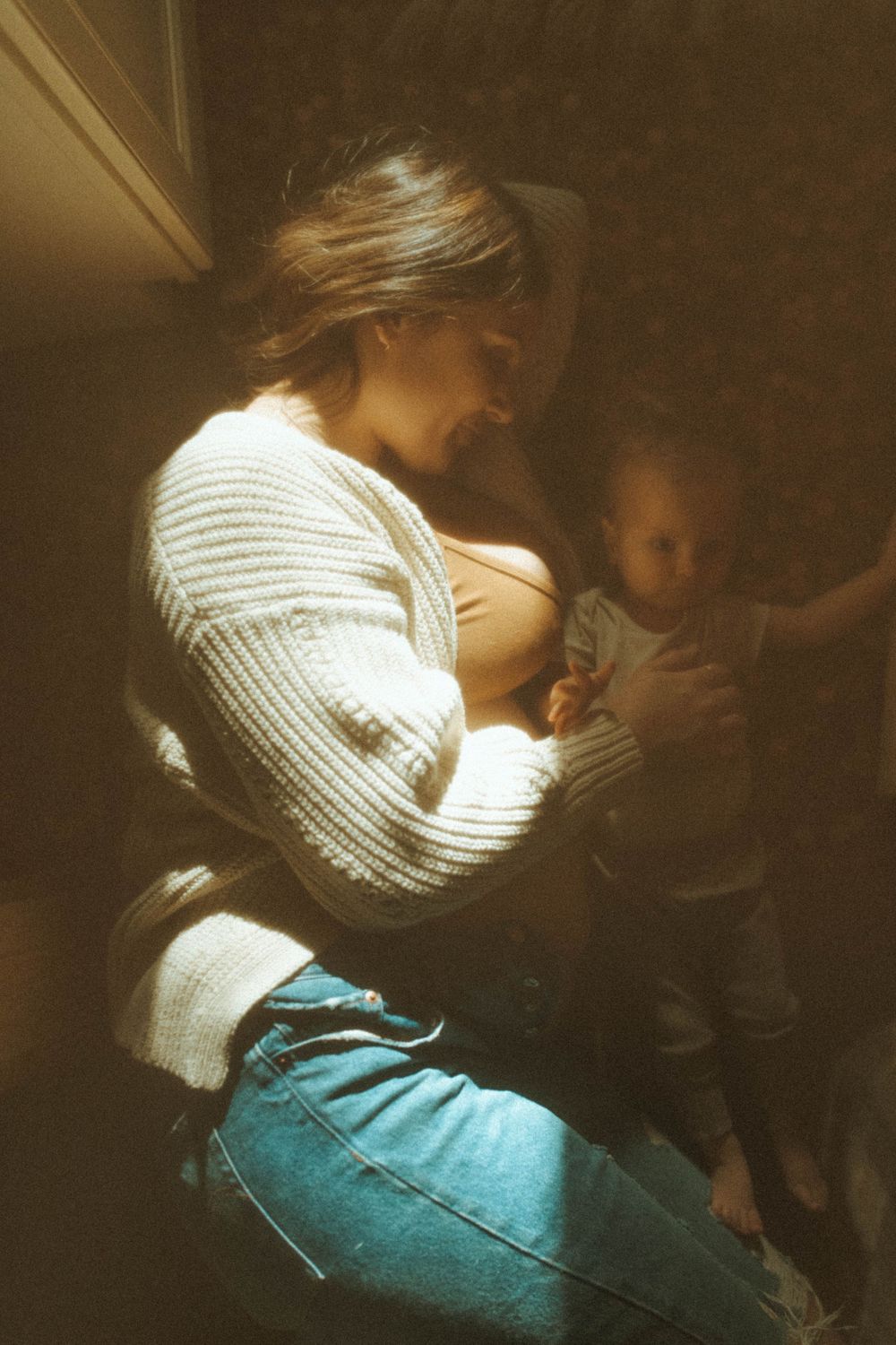Sepia-toned indoor portrait showing intimate family moment in natural window light.