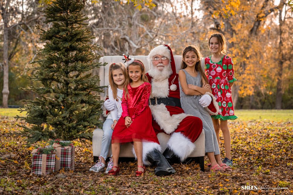 Festive group photo with Christmas decorations and evergreen tree in autumn setting.