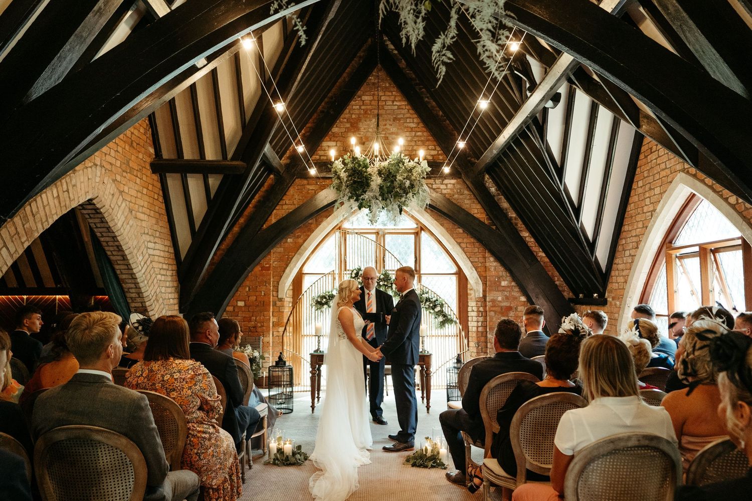 Wedding ceremony in rustic wooden chapel with dramatic lighting.
