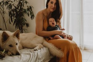 Baby and family dog sharing a tender moment in an indoor newborn session in Sydney & Northern Beaches, preserving joyful and loving memories
