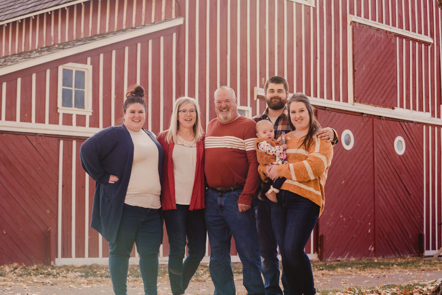 Family portrait session in front of red barn with white trim.