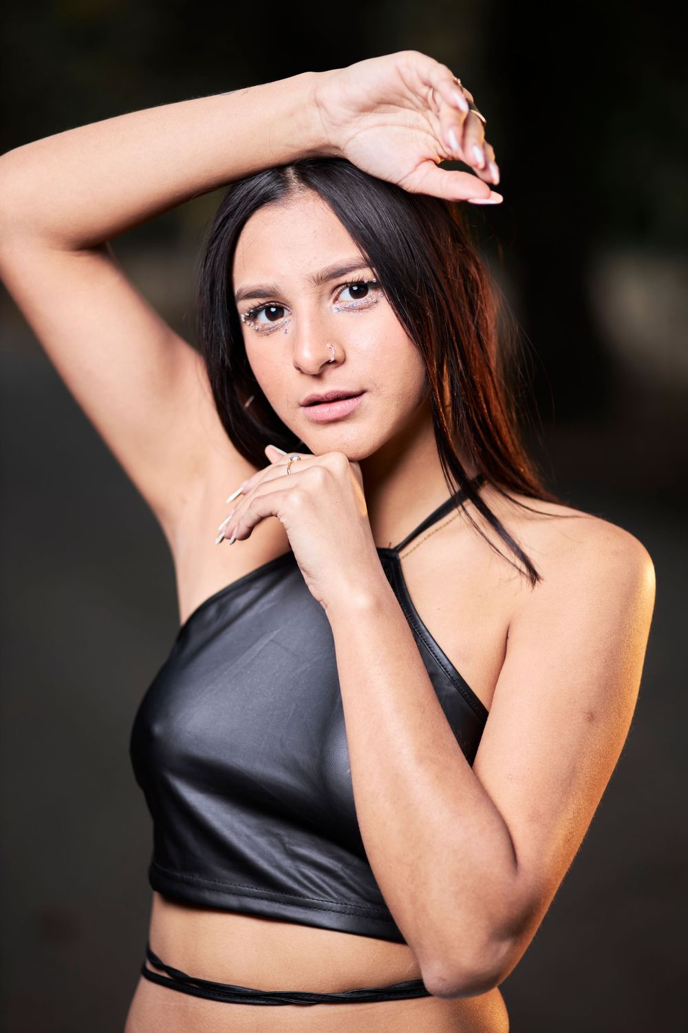 Close-up fashion portrait of model in black halter top against dark background.