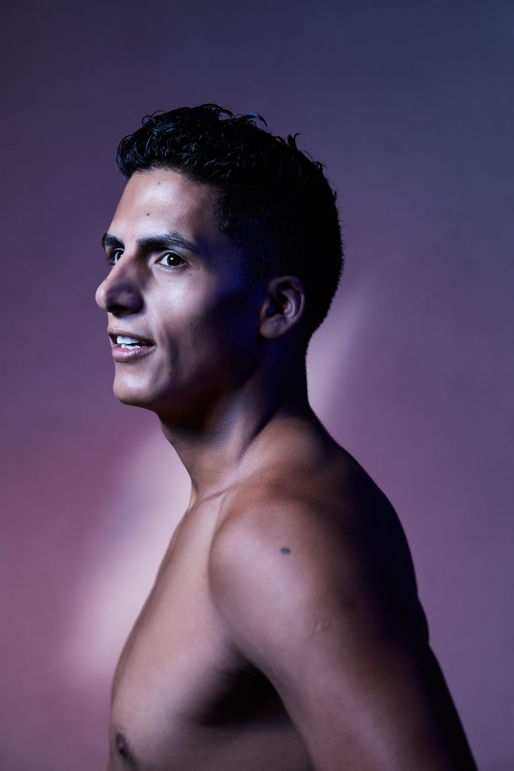 Profile portrait with natural lighting against purple gradient background.