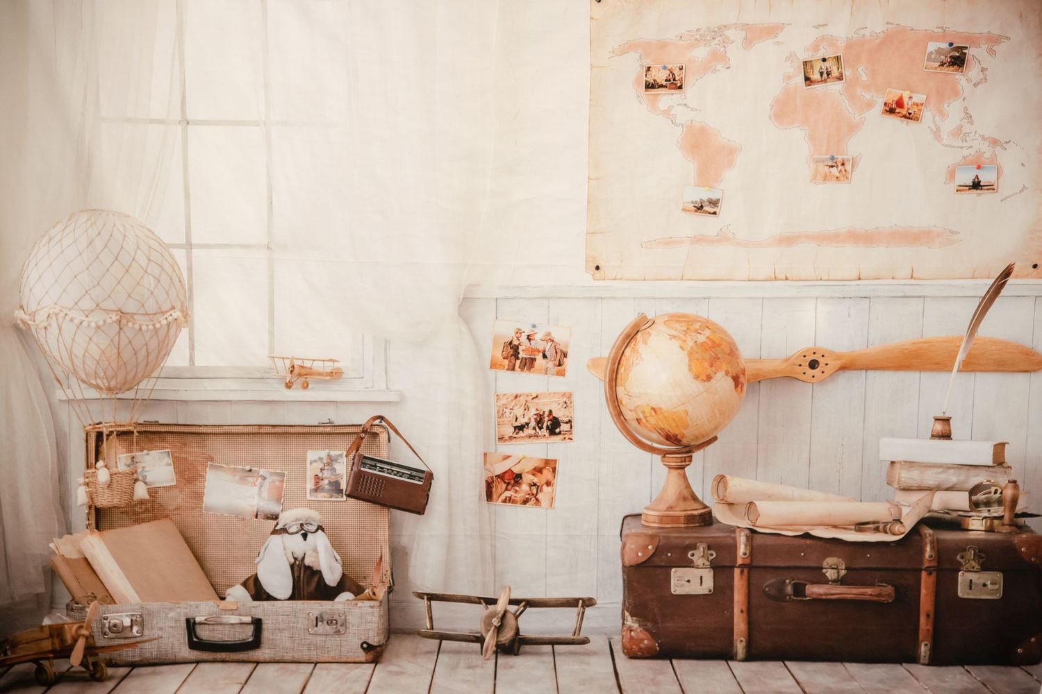 Travel themed decor display with antique suitcases, globe, and world map in warm tones.