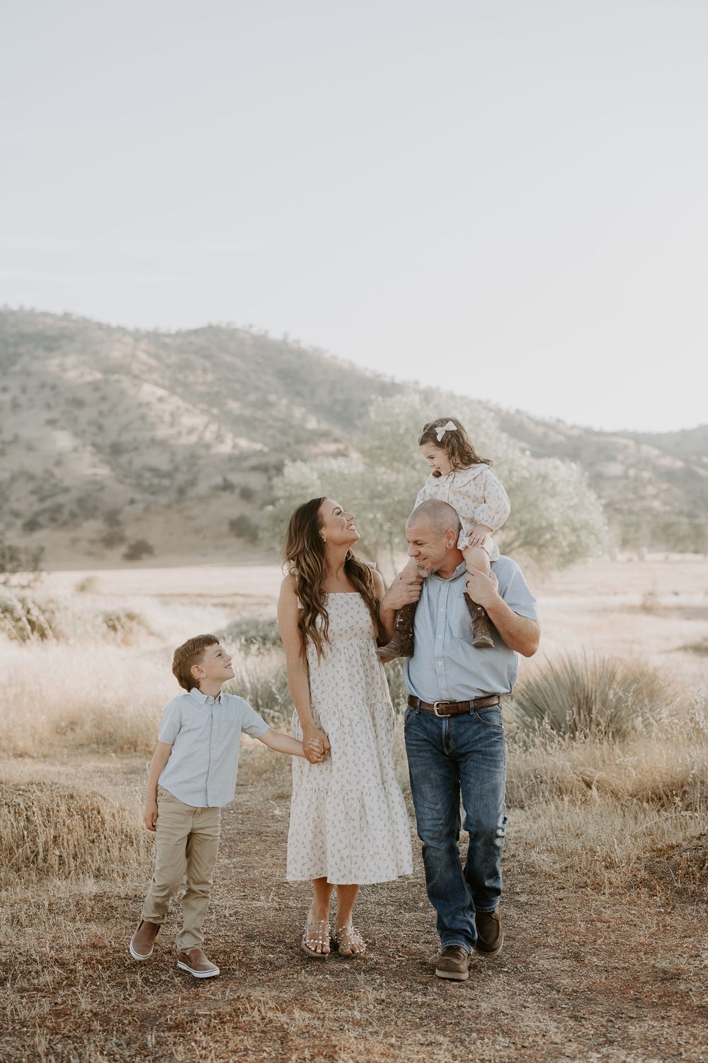 Family enjoying sunset walk together on desert trail with mountains in background.