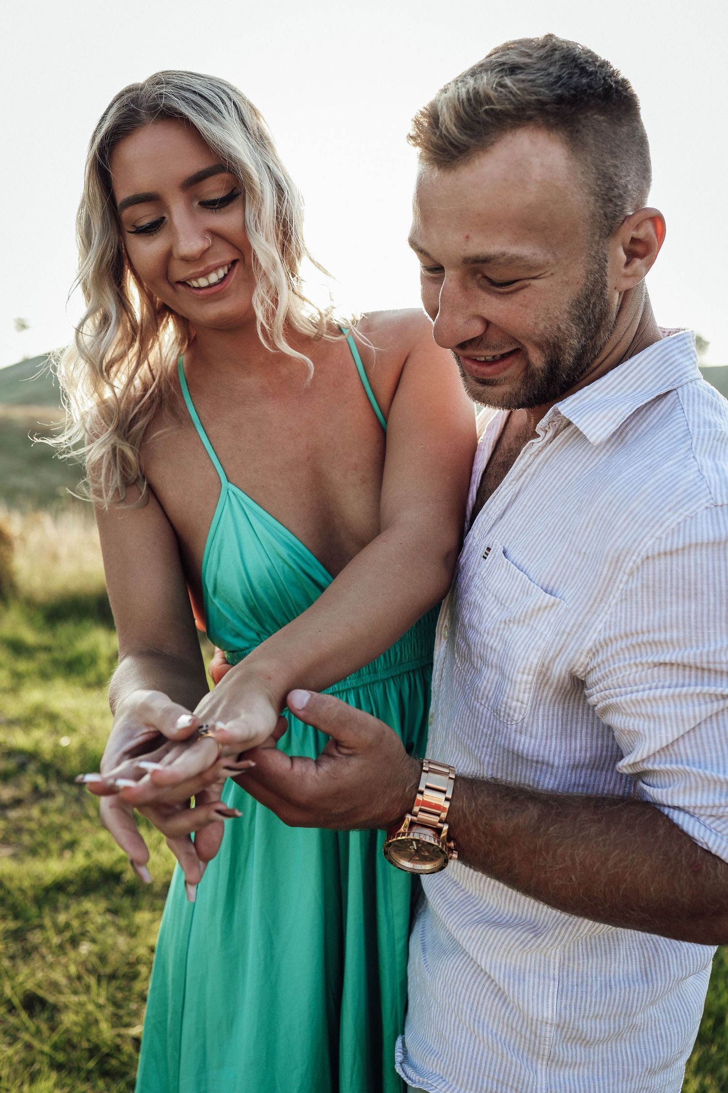 A couple shares a joyful moment looking at something in their hands outdoors.