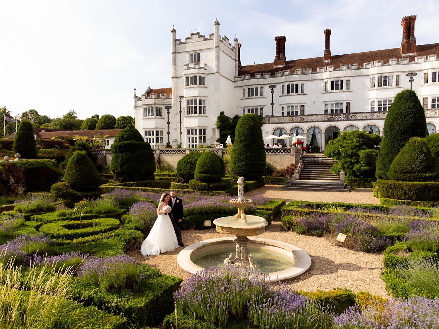 Elegant formal garden with stone fountain and topiary hedges at historic English manor house.
