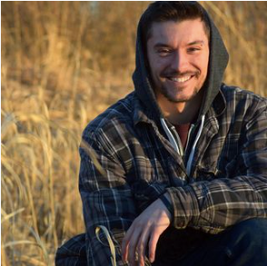 man in hoodie smiles at the camera