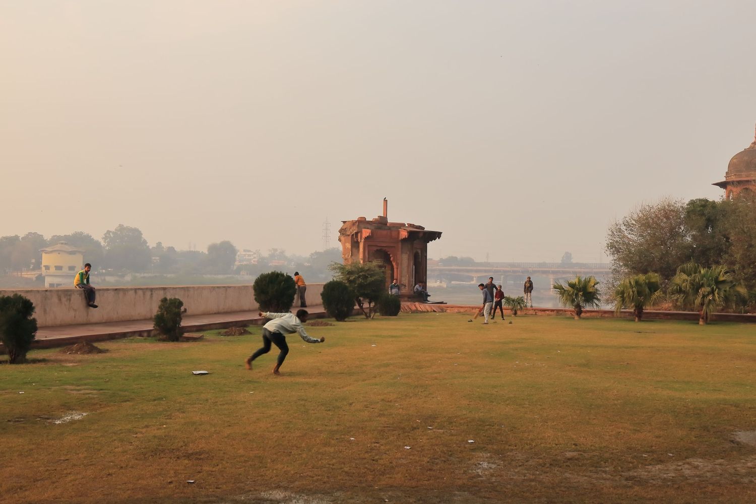 Grassy lawn in front of an ancient Indian monument with people enjoying the outdoor space.