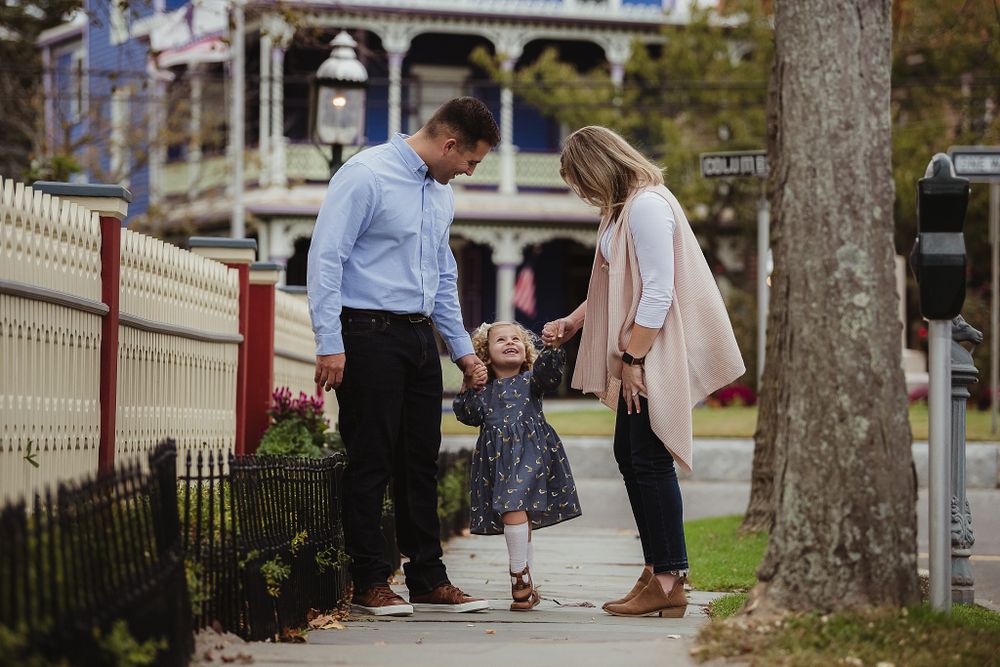 Candid family photo showing joyful interaction on a tree-lined sidewalk.