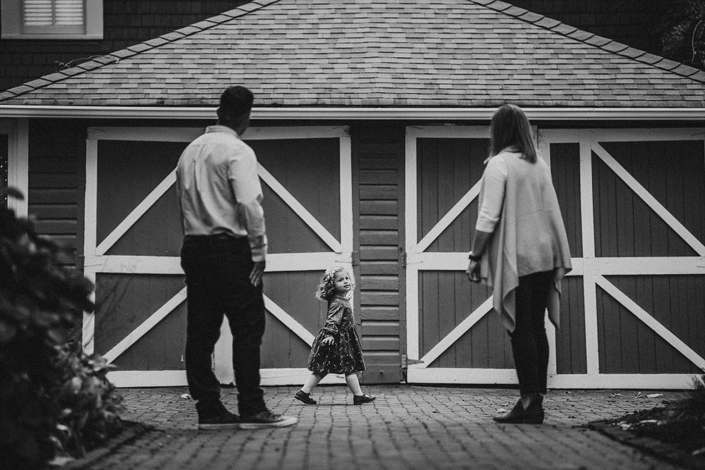 Black and white photo of a family walking together in front of barn-style garage doors.
