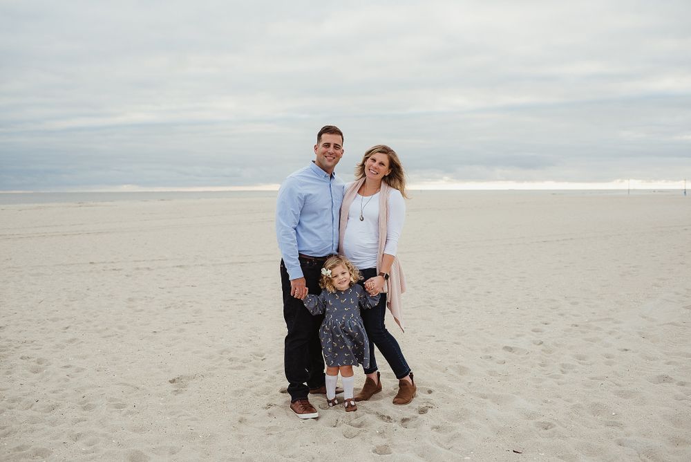 Family standing together on foggy beach during cloudy day.