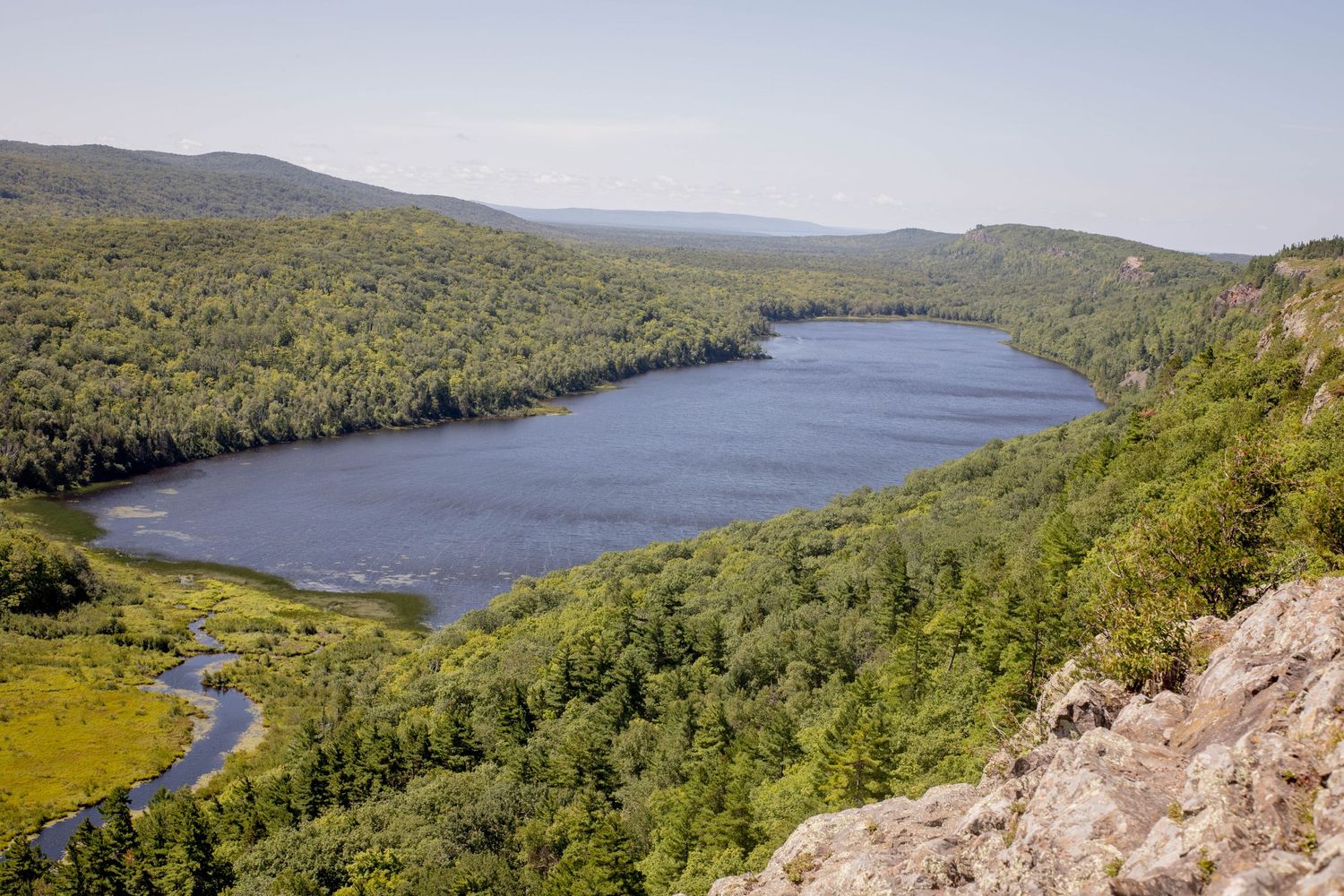 Aerial view of a blue lake surrounded by lush green forest and mountains.