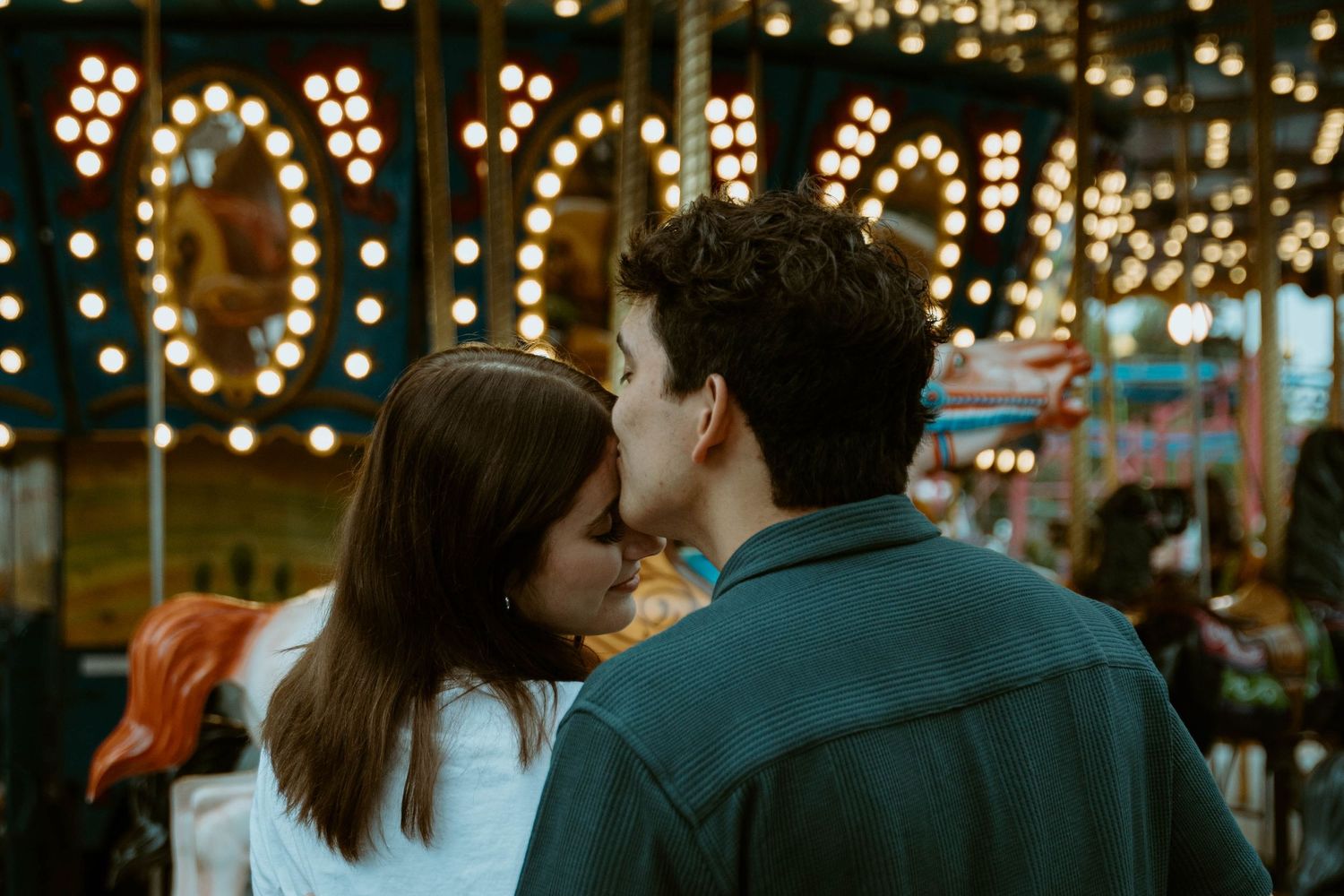 Romantic couple at carnival with glowing lights in background at K-Days in Edmonton, Alberta.