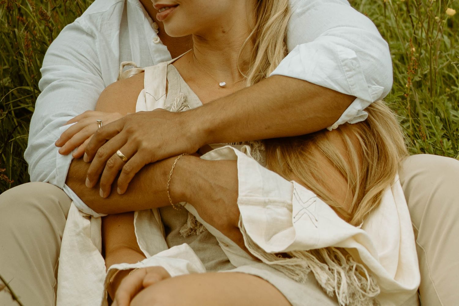 Intimate embrace in white clothing against grassy background with soft natural lighting in Iceland.