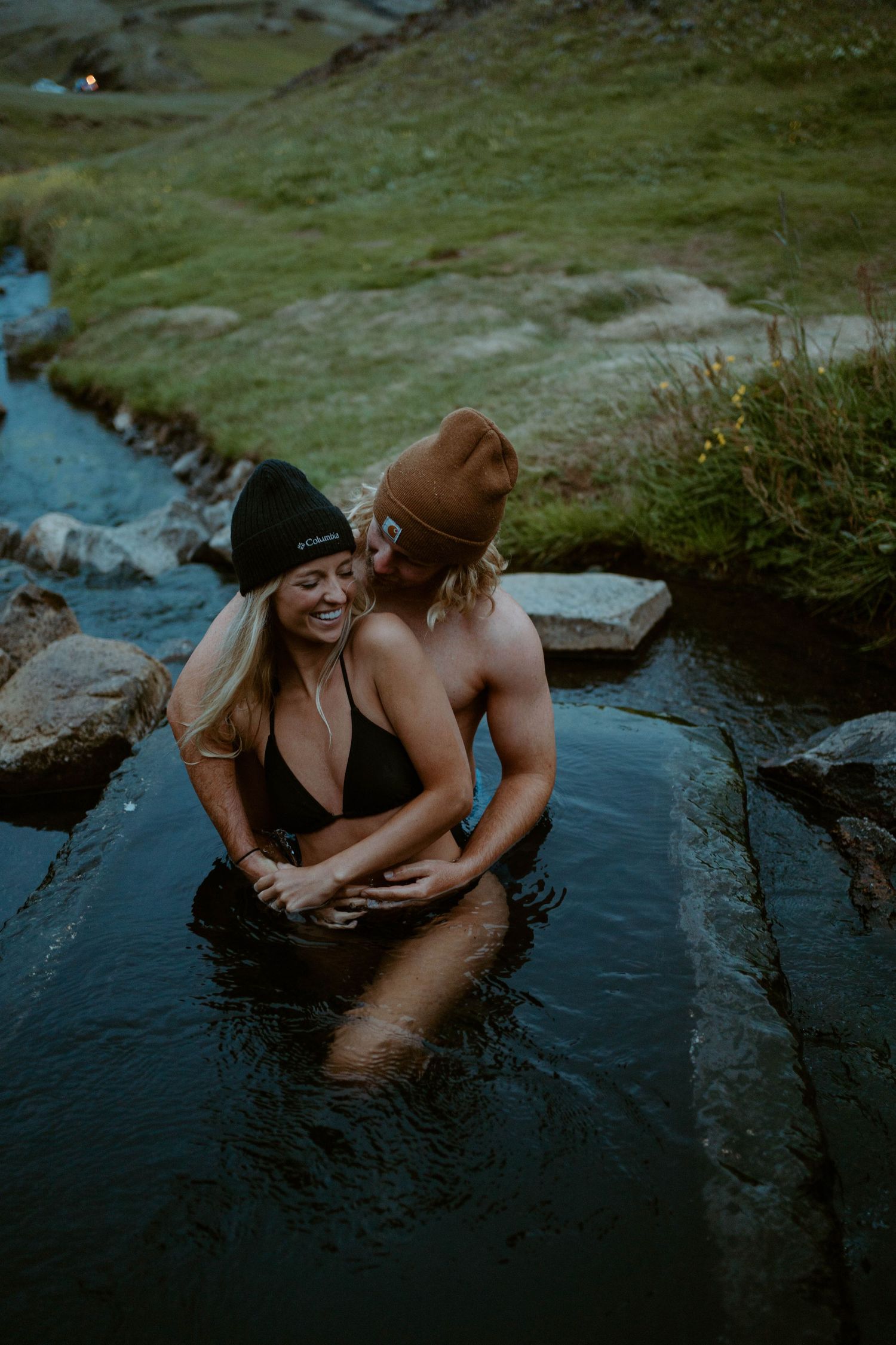 A couple shares an intimate moment while bathing in a natural hot spring in Iceland.