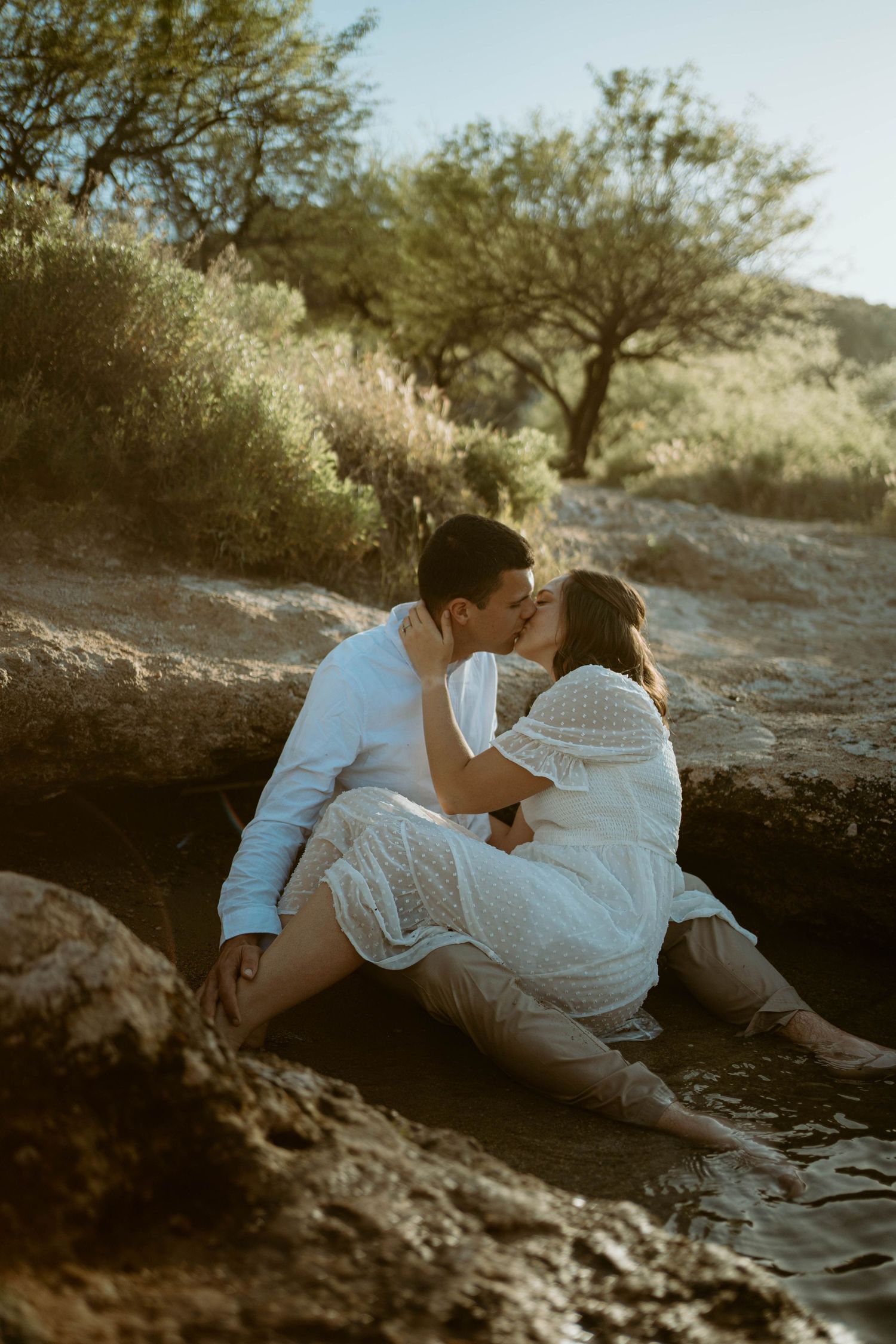 Romantic couples portrait on rocky terrain during golden hour.