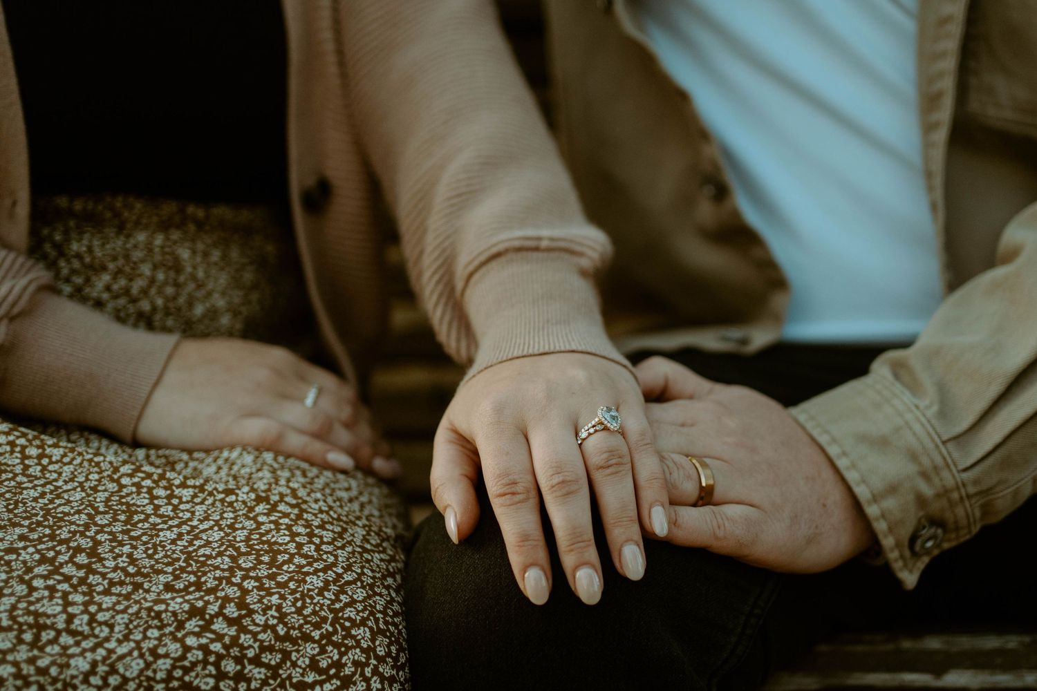 Close-up of intertwined hands with engagement rings showing a tender moment of connection.
