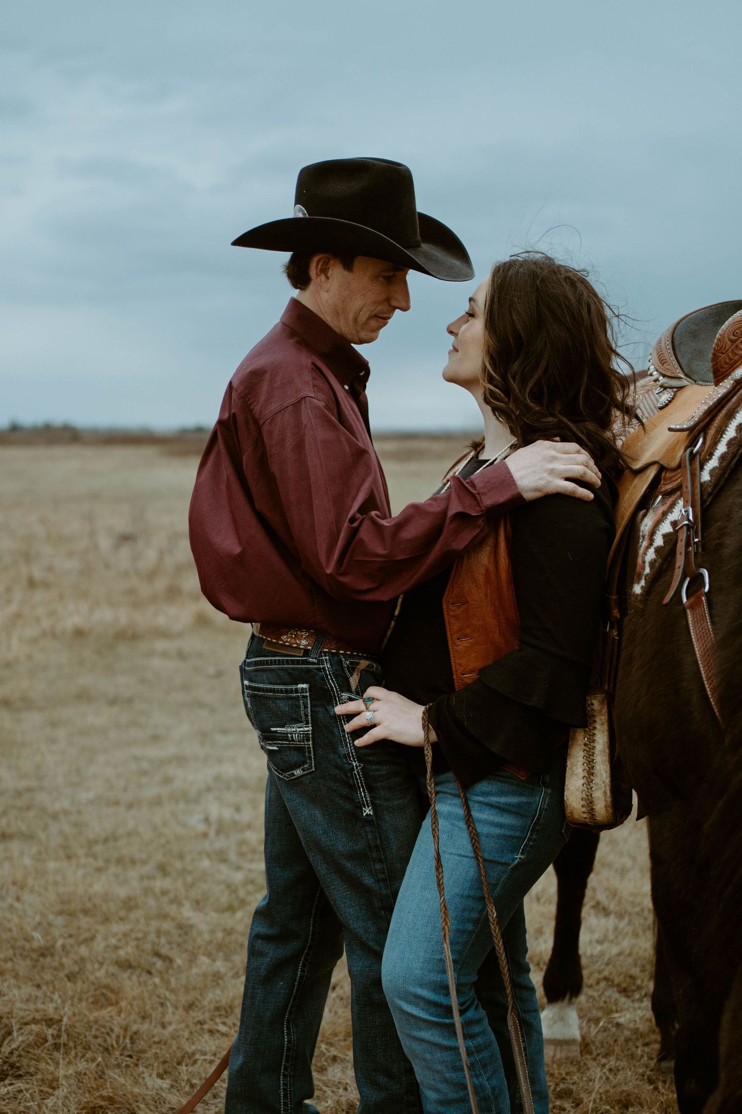 A romantic western scene with horses, cowboys and open plains under an overcast sky.