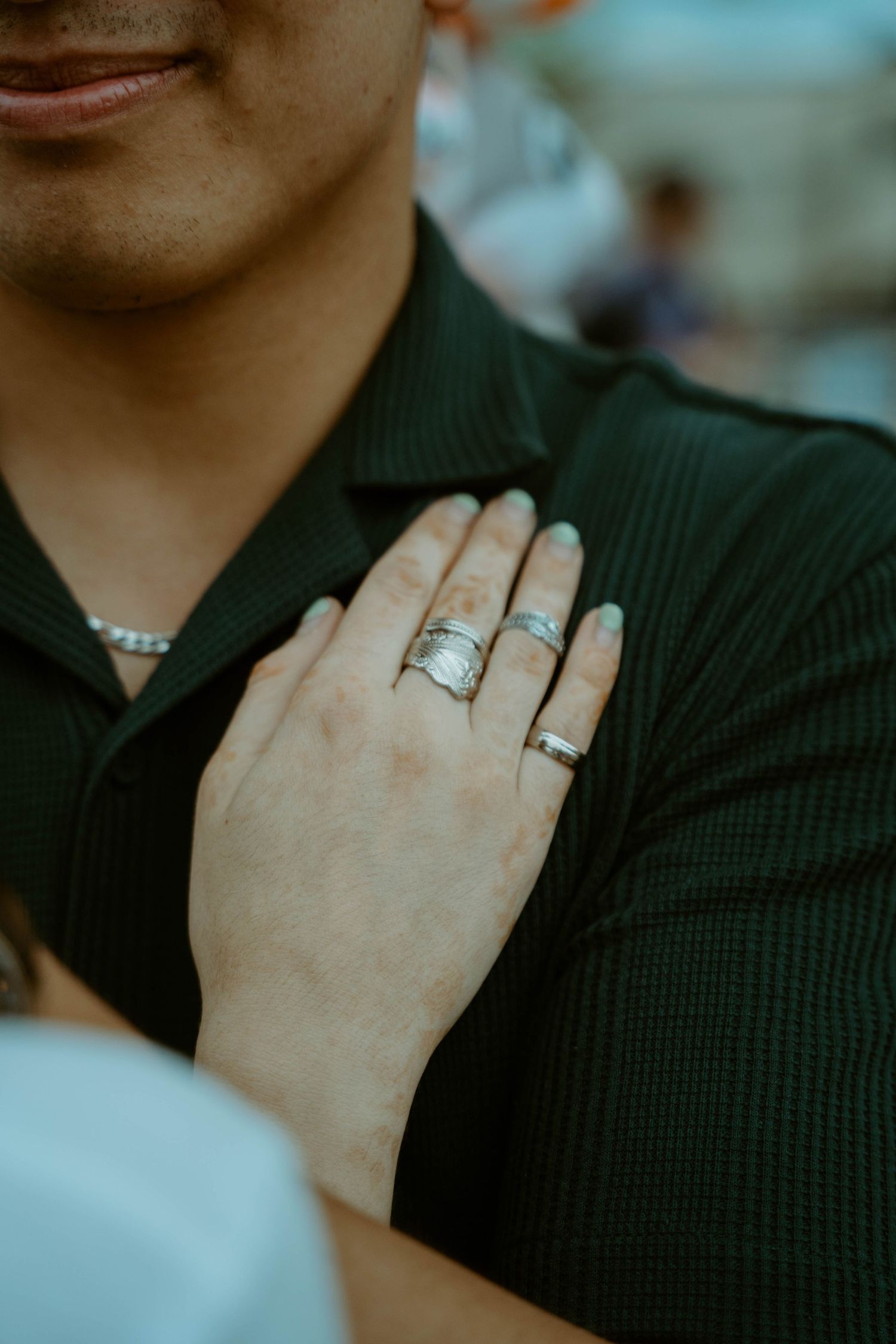 A close-up shot of hands wearing engagement rings against a dark colored shirt at K-Days in Edmonton, Alberta.